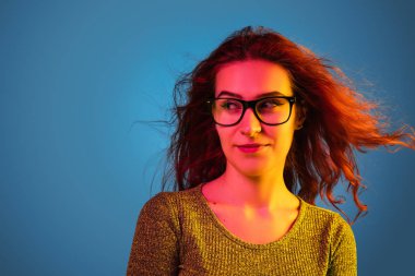 Beyaz kadın portresi mavi stüdyo arka planında neon ışıkta izole edilmiş.