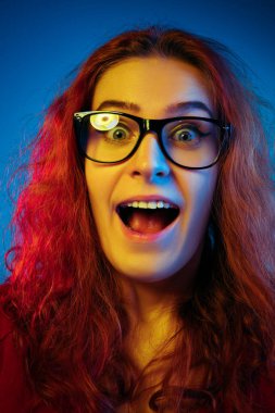 Beyaz kadın portresi mavi stüdyo arka planında neon ışıkta izole edilmiş.