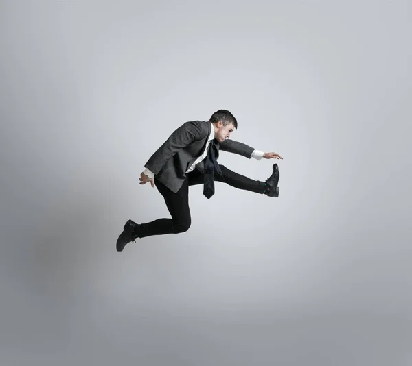Kaukasischer Mann in Bürokleidung läuft isoliert auf grauem Studiohintergrund — Stockfoto