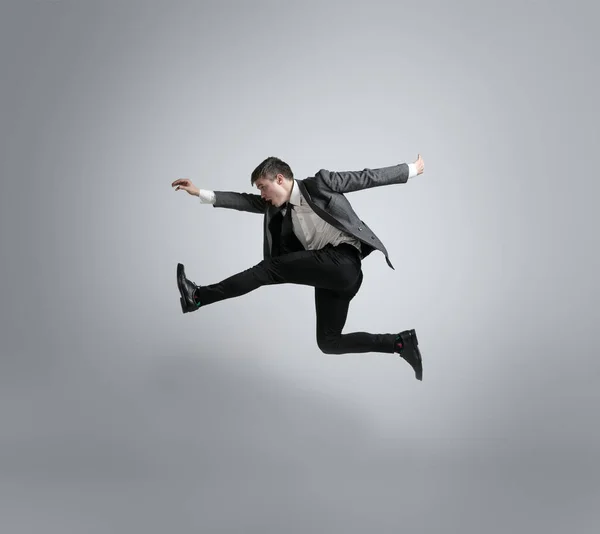 Homem caucasiano em roupas de escritório correndo isolado em fundo estúdio cinza — Fotografia de Stock
