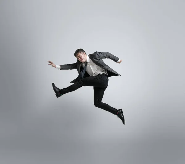 Homem caucasiano em roupas de escritório correndo isolado em fundo estúdio cinza — Fotografia de Stock