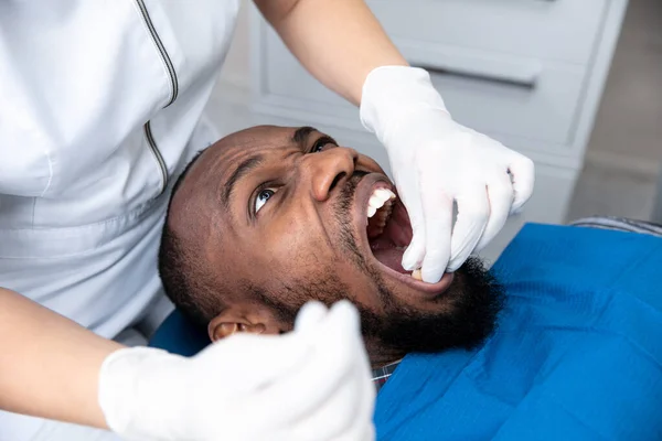Νεαρός αφροαμερικάνος που επισκέπτεται οδοντιατρικό γραφείο, φαίνεται φοβισμένος — Φωτογραφία Αρχείου