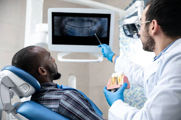 Giovane uomo afro-americano in visita dentista studio, utilizzando le tecnologie — Foto Stock
