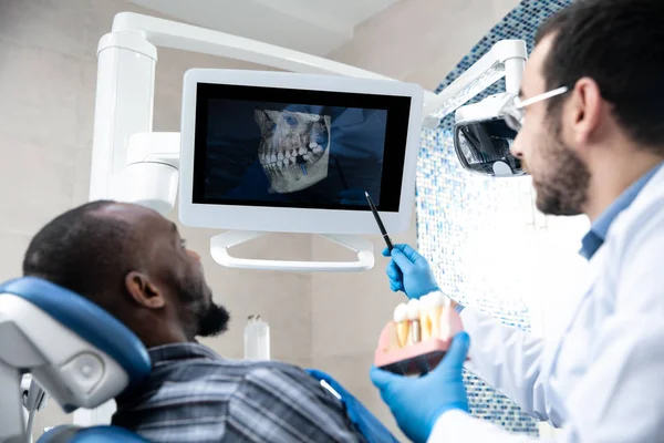 Jovem homem afro-americano visitando dentistas escritório, usando tecnologias — Fotografia de Stock