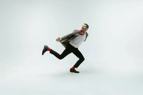 Jovem caucasiano homem em movimento flexível no fundo do estúdio branco — Fotografia de Stock