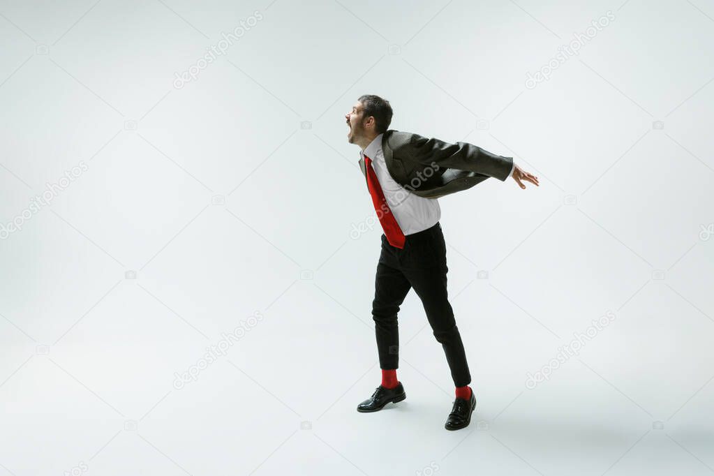 Young caucasian man moving flexible on white studio background
