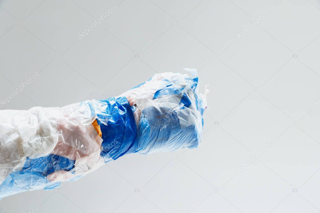 Big plastic hand made of garbage isolated on white studio background