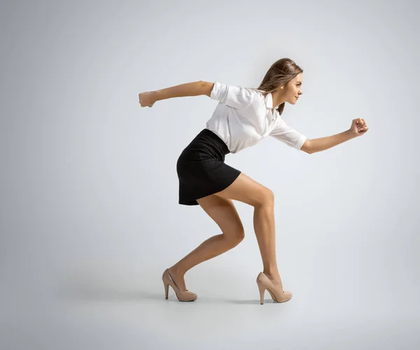 Mujer caucásica en ropa de oficina preparándose para correr aislado en fondo gris estudio — Foto de Stock