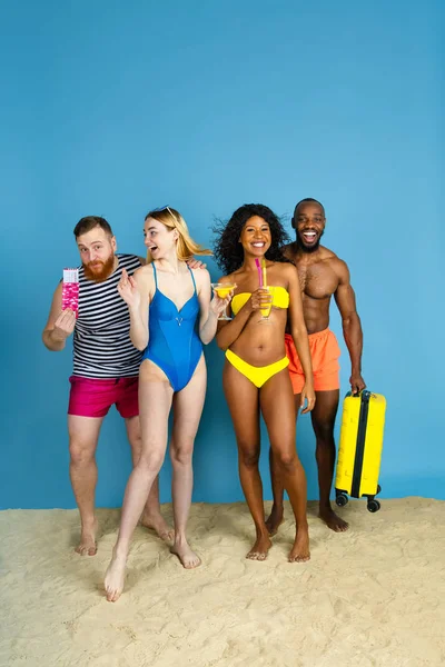 Happy young friends resting on blue studio background — Stock Photo, Image