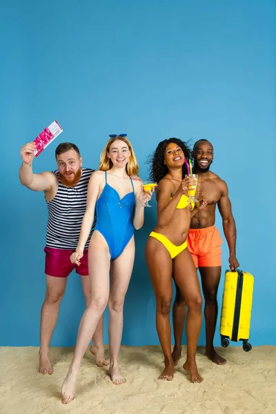 Happy young friends resting on blue studio background — Stock Photo, Image