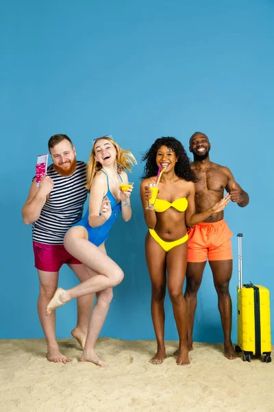 Happy young friends resting on blue studio background — Stock Photo, Image