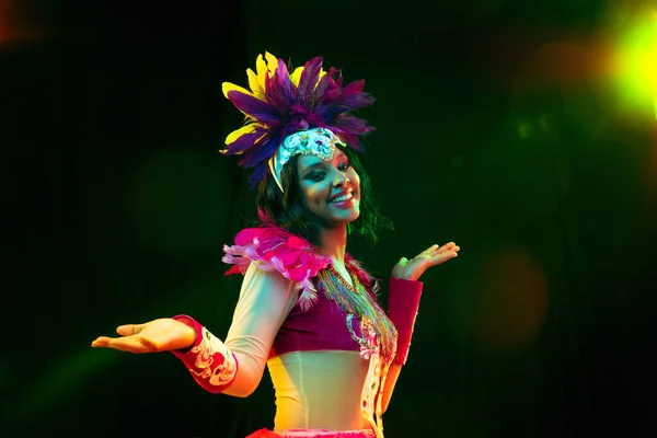 Hermosa mujer joven en máscara de carnaval y disfraz de mascarada en luces de colores — Foto de Stock