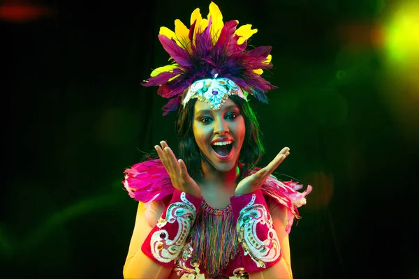 Hermosa mujer joven en máscara de carnaval y disfraz de mascarada en luces de colores — Foto de Stock