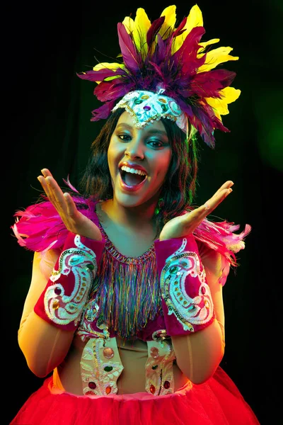 Schöne junge Frau in Karnevalsmaske und Maskerade Kostüm in bunten Lichtern — Stockfoto