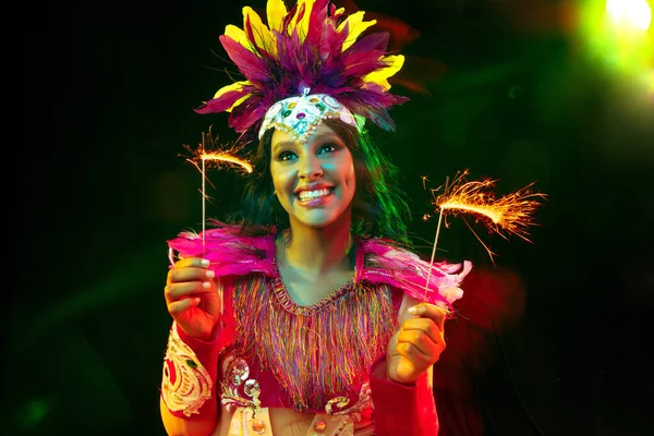 Hermosa mujer joven en máscara de carnaval y disfraz de mascarada en luces de colores — Foto de Stock