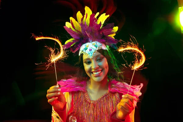 Belle jeune femme en masque de carnaval et costume de mascarade dans des lumières colorées — Photo