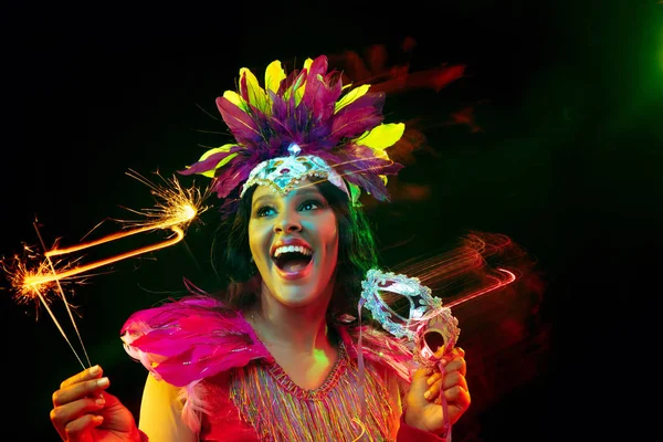 Belle jeune femme en masque de carnaval et costume de mascarade dans des lumières colorées — Photo