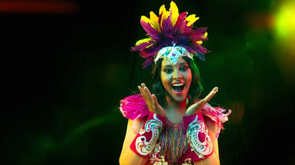Hermosa mujer joven en máscara de carnaval y disfraz de mascarada en luces de colores, volante — Foto de Stock