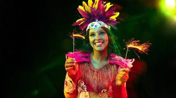 Hermosa mujer joven en máscara de carnaval y disfraz de mascarada en luces de colores, volante — Foto de Stock