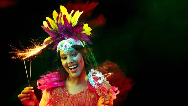 Karnaval maskeli güzel genç bir kadın ve renkli ışıklar altında maskeli balo kostümü. — Stok fotoğraf