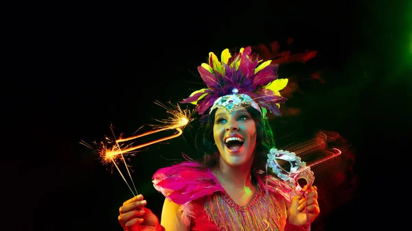 Mooie jonge vrouw in carnaval masker en maskerade kostuum in kleurrijke lichten, flyer — Stockfoto
