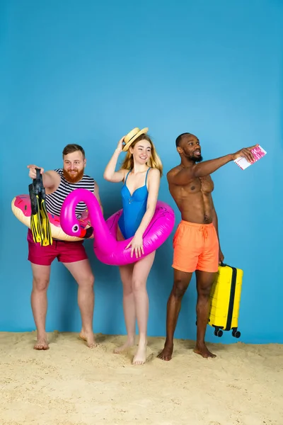 Jovens amigos felizes descansando no fundo do estúdio azul — Fotografia de Stock