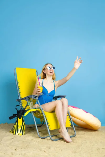 Happy young woman resting on blue studio background — Stock Photo, Image