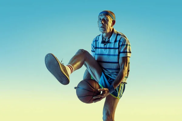 シニア男プレーバスケットボールでスポーツウェアでグラデーション背景とネオンライト — ストック写真