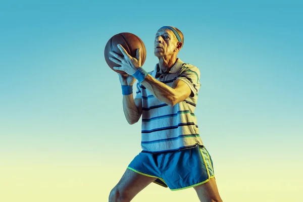 Senior man basketbal spelen in sportschoeisel op gradiënt achtergrond en neon licht — Stockfoto