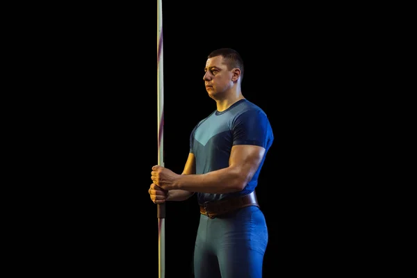 Atleta masculino practicando en lanzar jabalina aislada sobre fondo de estudio negro en luz de neón —  Fotos de Stock