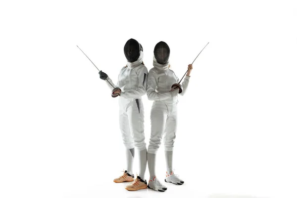 Teen girls in fencing costumes with swords in hands isolated on white background, flyer — Stock Photo, Image