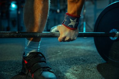 Spor salonunda ağırlık kaldırmada antrenman yapan beyaz bir adam.