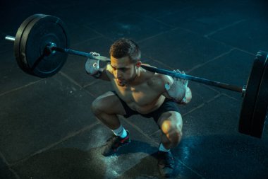 Spor salonunda ağırlık kaldırmada antrenman yapan beyaz bir adam.