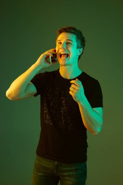 Beyaz adam portresi yeşil stüdyo arka planında neon ışıkta izole edilmiş.