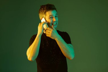 Beyaz adam portresi yeşil stüdyo arka planında neon ışıkta izole edilmiş.