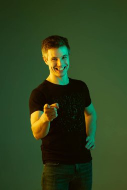 Beyaz adam portresi yeşil stüdyo arka planında neon ışıkta izole edilmiş.