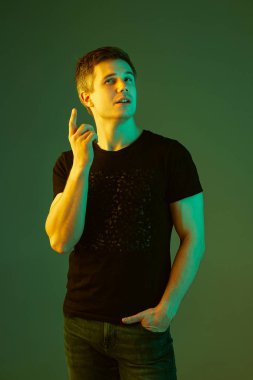 Beyaz adam portresi yeşil stüdyo arka planında neon ışıkta izole edilmiş.