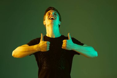 Beyaz adam portresi yeşil stüdyo arka planında neon ışıkta izole edilmiş.