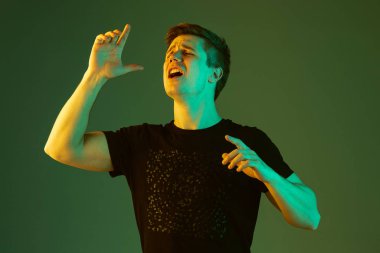 Beyaz adam portresi yeşil stüdyo arka planında neon ışıkta izole edilmiş.