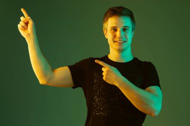 Beyaz adam portresi yeşil stüdyo arka planında neon ışıkta izole edilmiş.