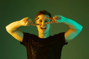 Beyaz adam portresi yeşil stüdyo arka planında neon ışıkta izole edilmiş.