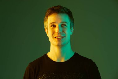 Beyaz adam portresi yeşil stüdyo arka planında neon ışıkta izole edilmiş.