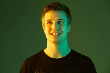 Beyaz adam portresi yeşil stüdyo arka planında neon ışıkta izole edilmiş.