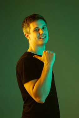 Beyaz adam portresi yeşil stüdyo arka planında neon ışıkta izole edilmiş.