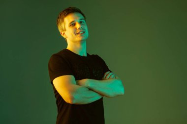 Beyaz adam portresi yeşil stüdyo arka planında neon ışıkta izole edilmiş.