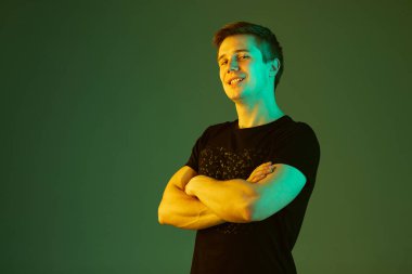 Beyaz adam portresi yeşil stüdyo arka planında neon ışıkta izole edilmiş.