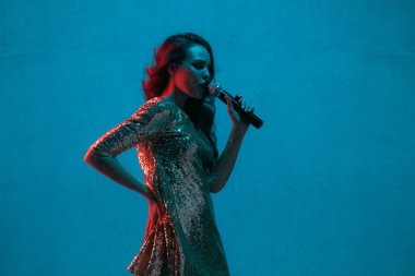 Caucasian female singer portrait isolated on blue studio background in neon light