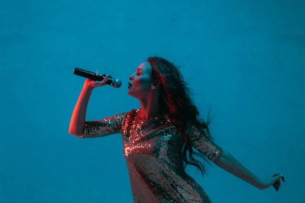 Kaukasische zangeres portret geïsoleerd op blauwe studio achtergrond in neon licht — Stockfoto