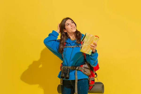 Ganzkörperporträt einer fröhlichen jungen kaukasischen Touristenmädchen isoliert auf gelbem Hintergrund — Stockfoto
