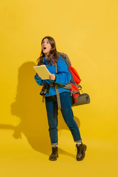 Full length portrait of a cheerful young caucasian tourist girl isolated on yellow background — Stock Photo, Image